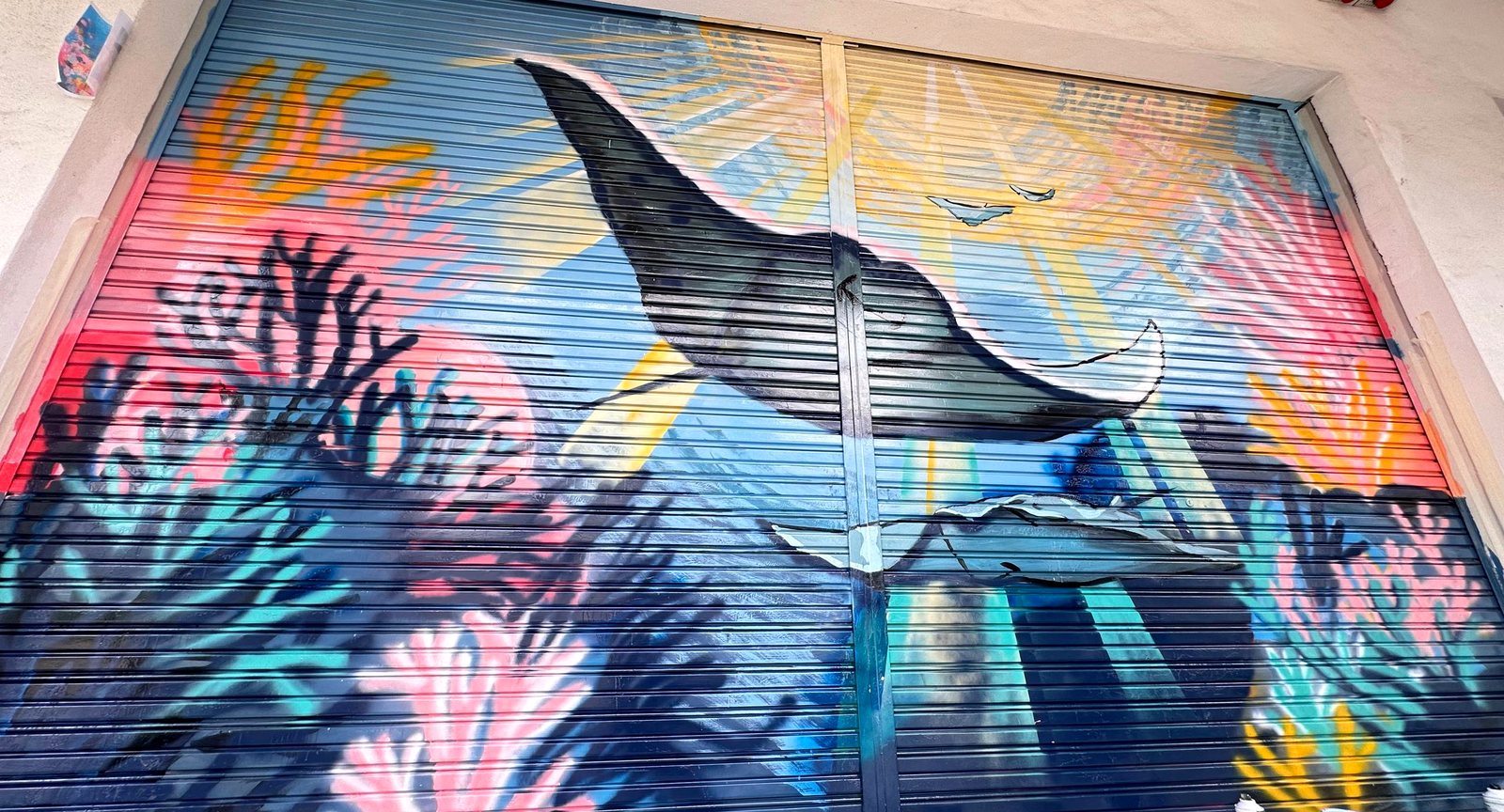 Whale and ocean mural painted on a metal roller shutter