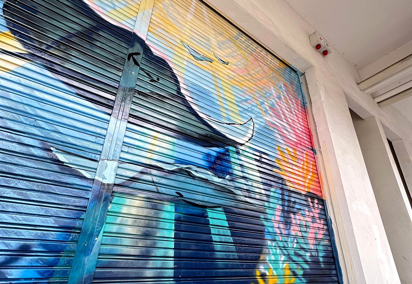 Ocean mural painting in progress on a shopfront metal shutter
