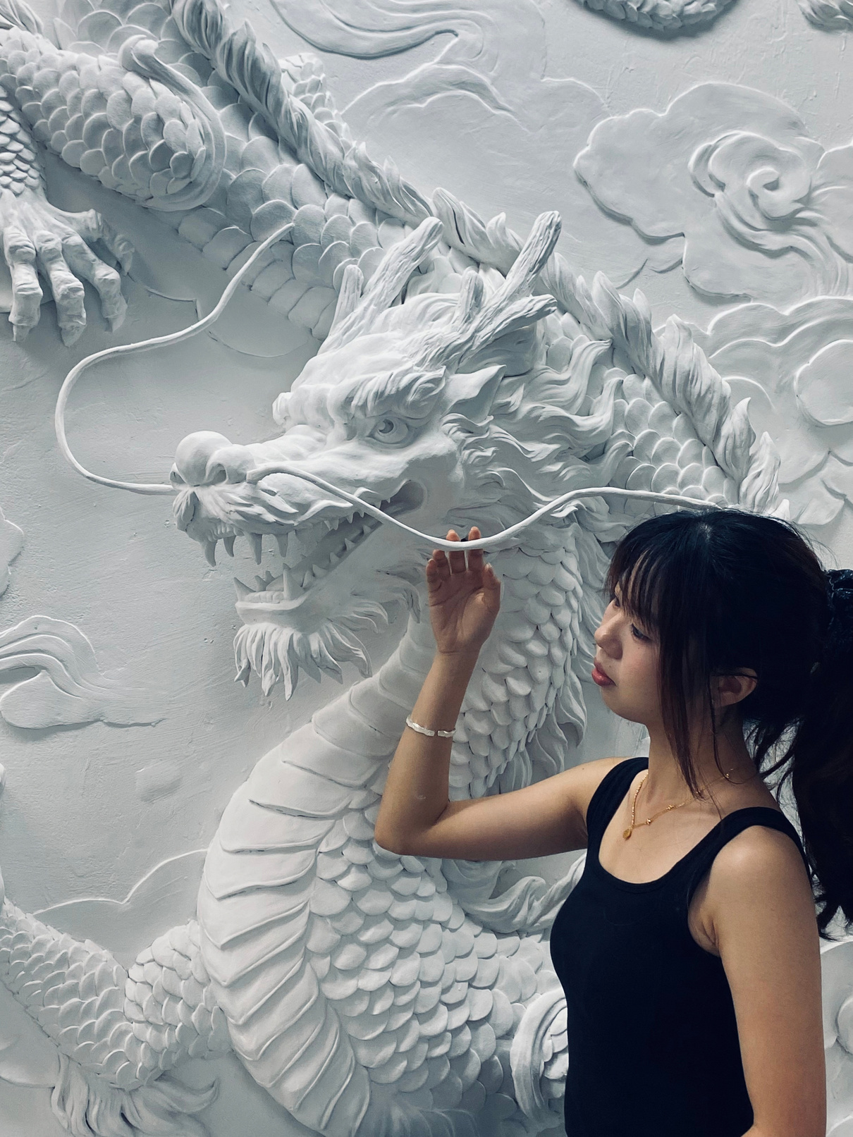 Person working on a white dragon wall relief