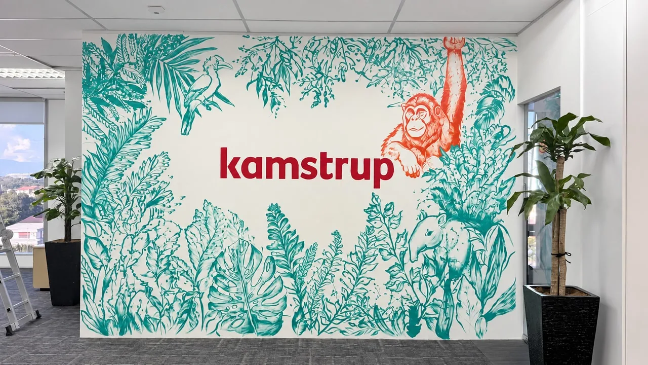 Botanical wall mural with teal leaves, orange orangutan and red brand lettering