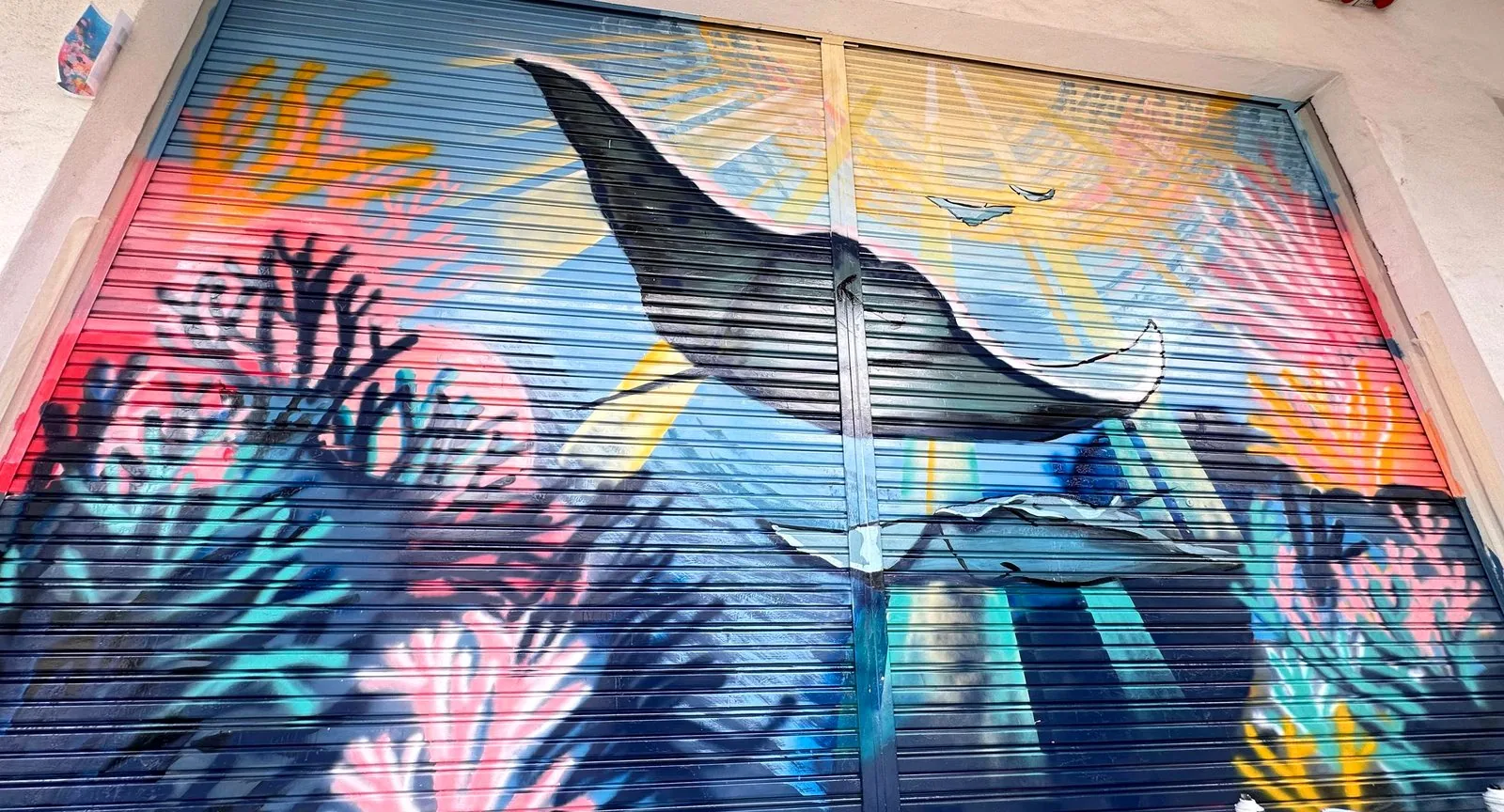Whale and ocean mural painted on a metal roller shutter